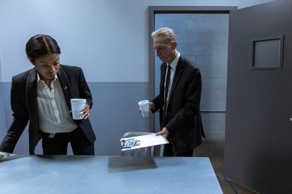 Two professionals in a secure office setting discussing confidential documents over coffee.