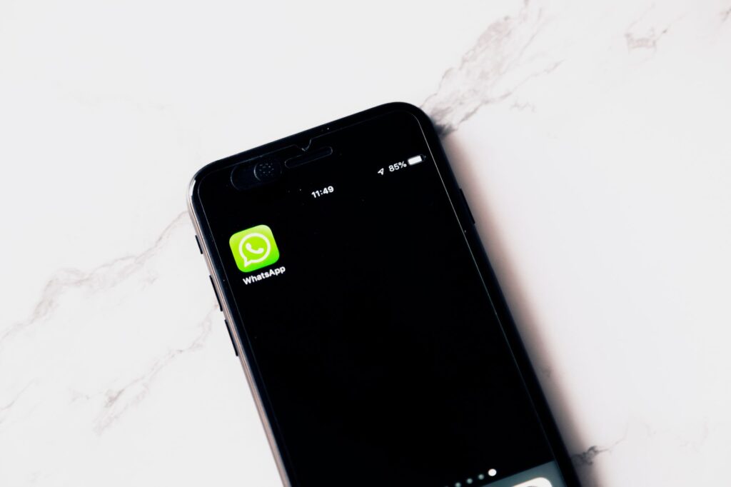 Close-up image of a smartphone displaying WhatsApp on a white table.